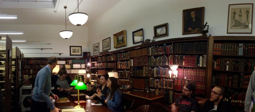 Secret Pittsburgh class students looking at some of the Carnegie Library's oldest books in the Oliver Room with the archivist. Photo by Olivia DiPrimio.