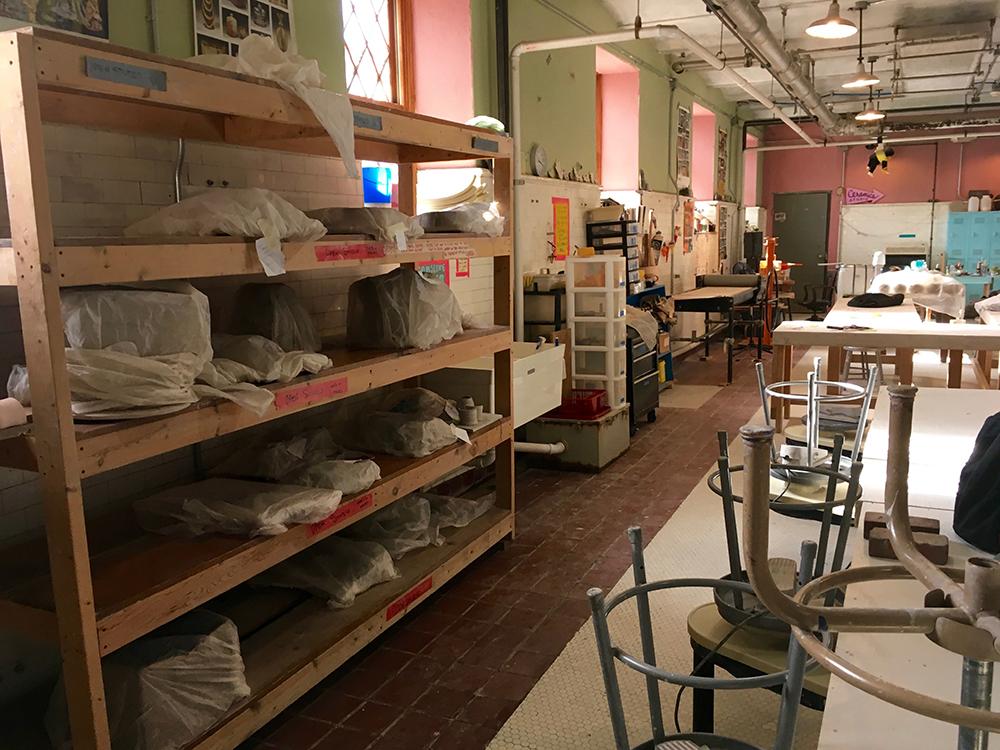 Ceramic studio with clay on a shelves and stools overturned on tables. Photo by Arielle Berk.