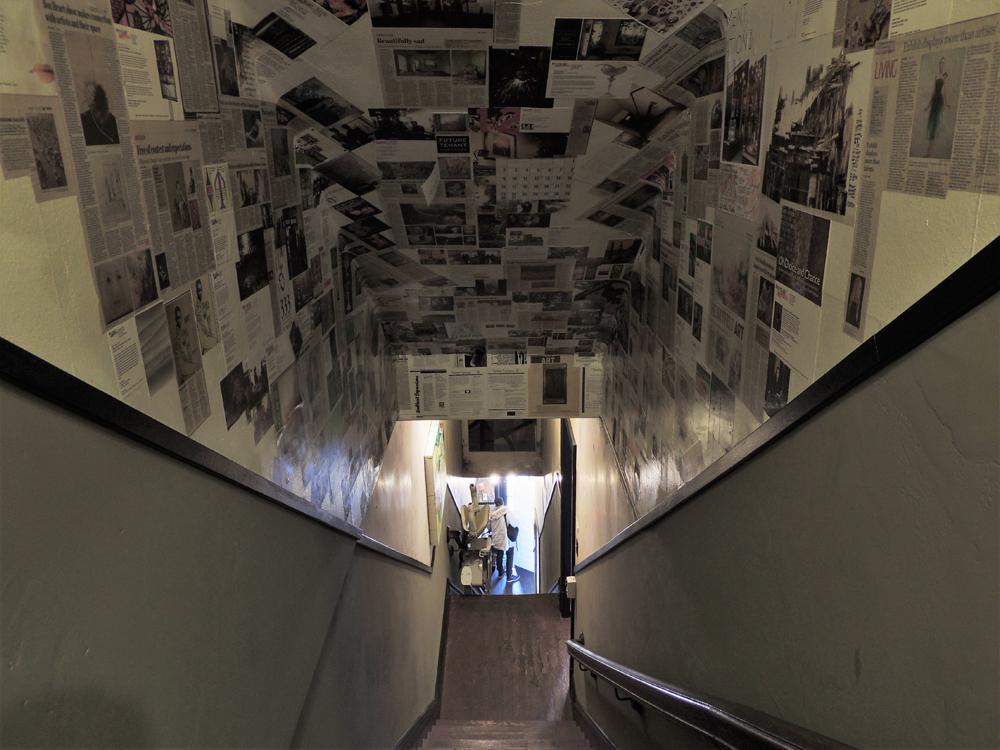 The stairwell in Boxheart displaying newspaper clippings on the ceiling. Photo by Lauren Chronister.