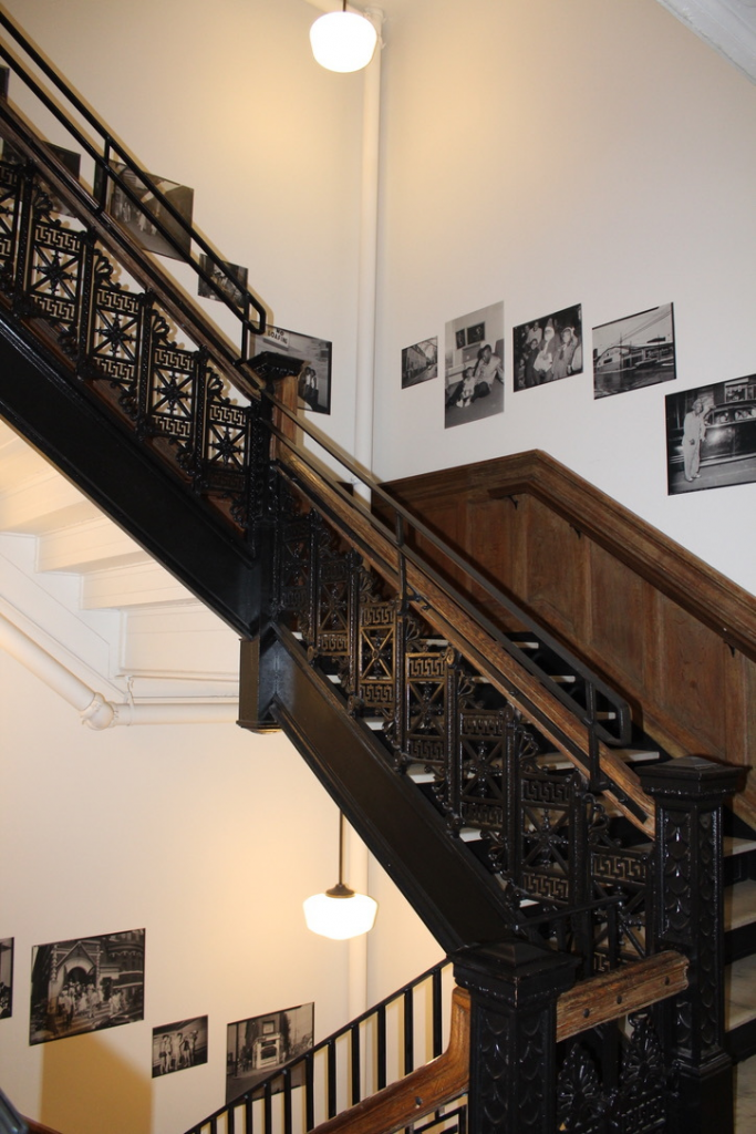 The stairs leading to the hotel rooms are lined with photographs from the Teenie Harris archive collection. The photos are portraits of YMCA members. Photo by Emily Meehan, 2019.